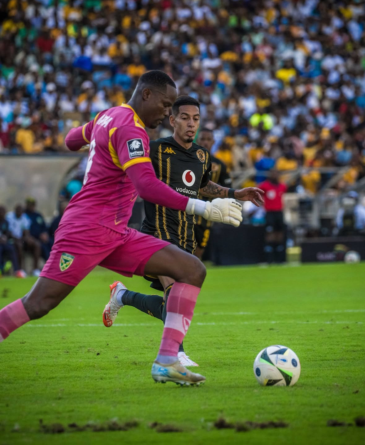 Two soccer players in action on a field with a crowd in the background