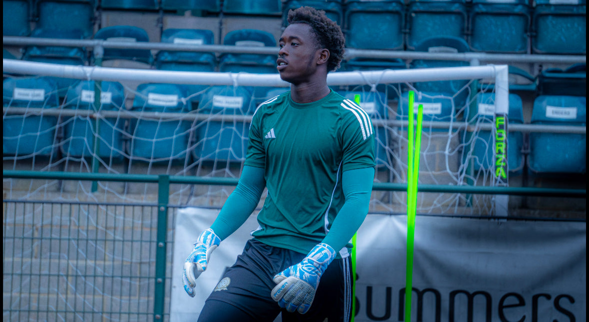 Person in green sports jersey sitting on a bench with stadium seats in the background